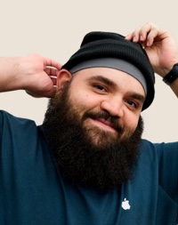 Portrait of a smiling Apple Retail team member with a full beard and wearing a knit cap.