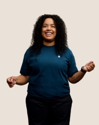 Portrait of a smiling Apple Retail team member with long, curly dark hair.