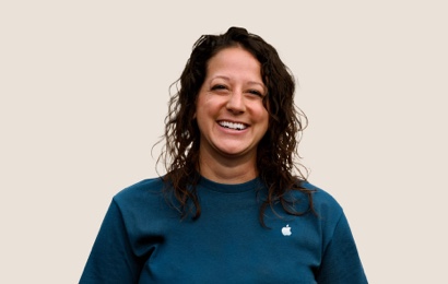 Portrait of a smiling Apple Retail team member with long, wavy dark hair.