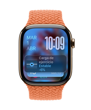 Apple Watch de titanio color oro con una correa trenzada mandarina, cuya carátula muestra la fecha en la esquina superior izquierda, la hora con números angostos en la esquina superior derecha y debajo el widget Carga de Entrenamiento, todo con el nuevo diseño translúcido en Liquid Glass