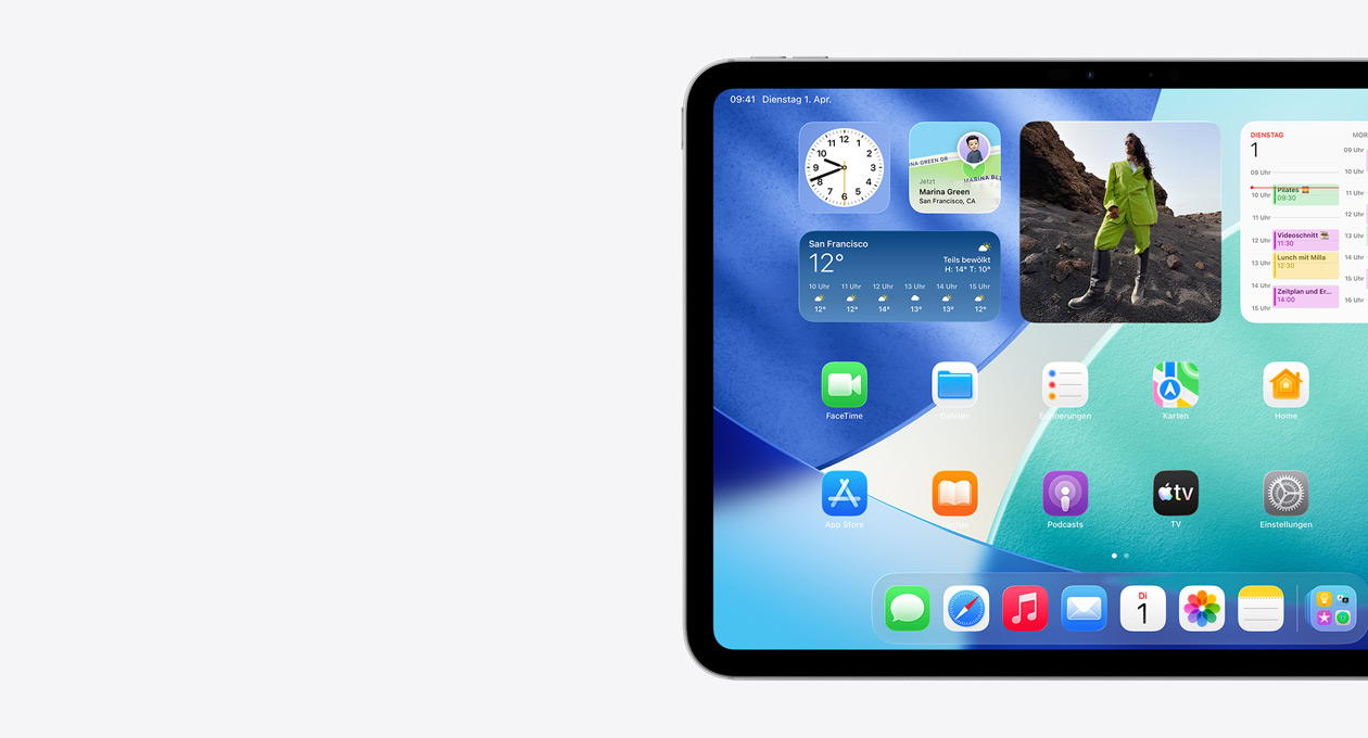 Ein iPad im Querformat, nur die linke Seite des Displays ist zu sehen, darauf der Homescreen mit gestapelten Widgets, einschließlich transluzenter Uhr mit Liquid Glass Effekt, „Wo ist?“ App, Wetter Widget, zwei Reihen kleinerer Apps und des Dock
