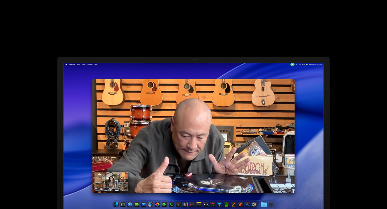 While on a video call, a person at a music store looks closely at a turntable, he remains centred in the frame thanks to the Center Stage camera