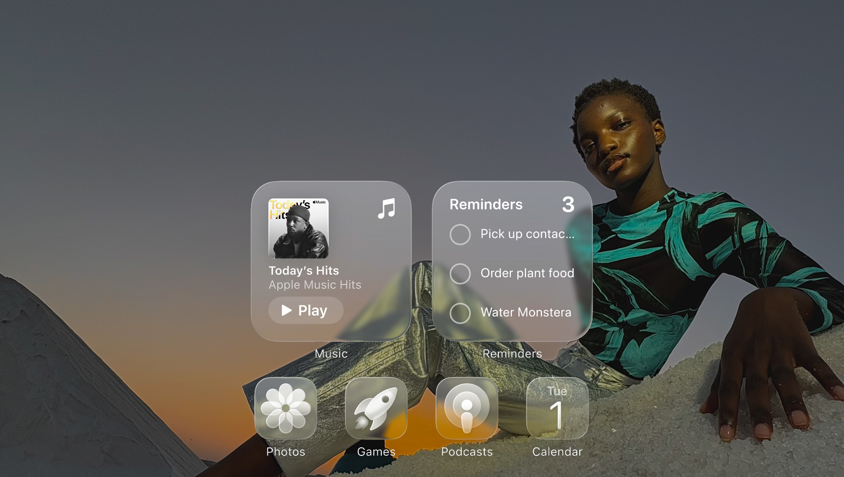 Liquid Glass képernyő az Apple Music, az Emlékeztetők, a Fotók, a Játékok, a Podcastok és a FaceTime app áttetsző ikonjaival, amelyeken átszűrődik a háttérkép