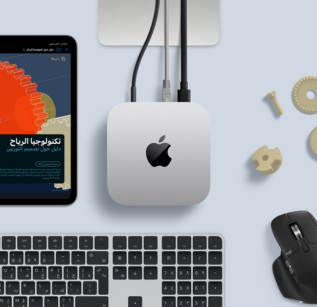 لقطة علوية لجهاز Mac&nbsp;mini فضي اللون ضمن إعداد مكتبي مع لوحة مفاتيح لاسلكية باللونين الأسود والفضي وماوس لاسلكي أسود وجهاز iPad