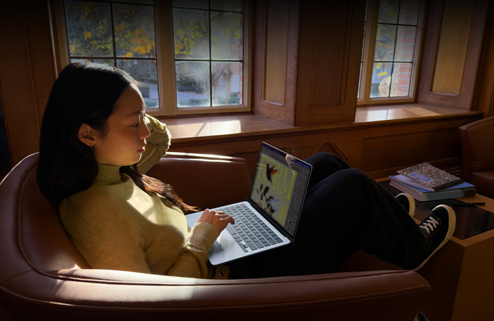 شخص يجلس على كرسي ويستخدم جهاز MacBook Air‏