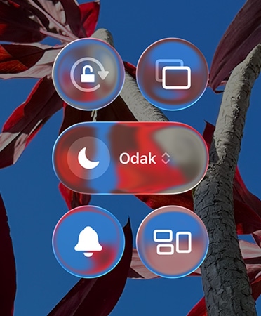 Renkli iPhone Ana Ekranı’nda şeffaf Liquid Glass, uygulamalar ve araç takımları gösteriliyor