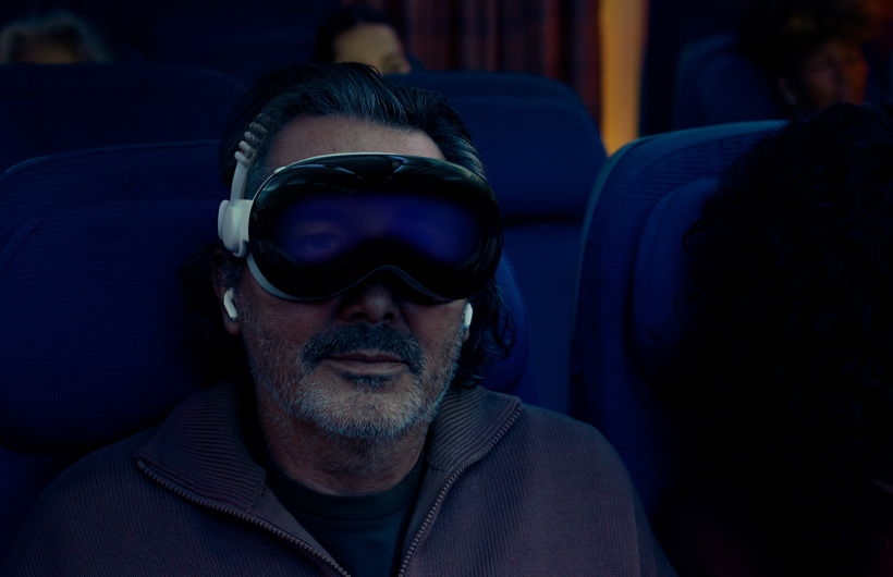 شخص يجلس في طائرة ويضع على وجهه Apple&nbsp;Vision&nbsp;Pro تم تجميعه مع الحزام الثنائي المغزول