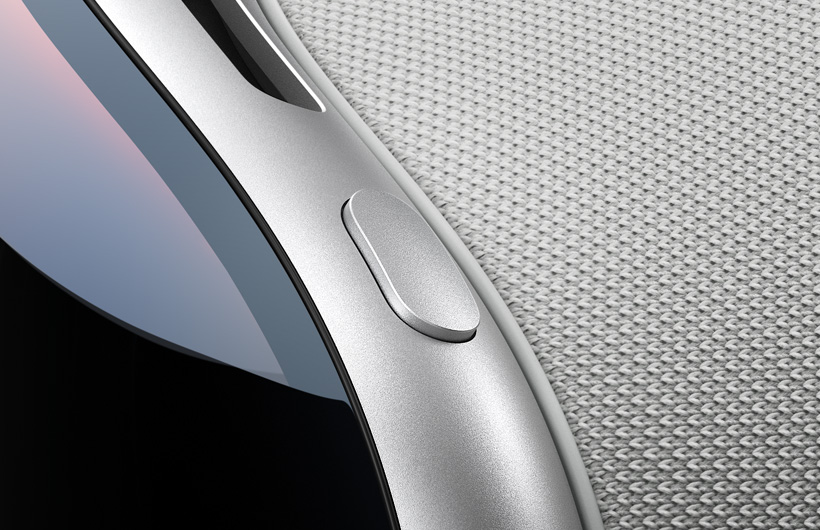 Close-up view shows the curved top-left corner of Apple Vision Pro, the top button has the same aluminum finish as the Apple Vision Pro frame, the curved glass of the front and part of the top air vent are also shown
