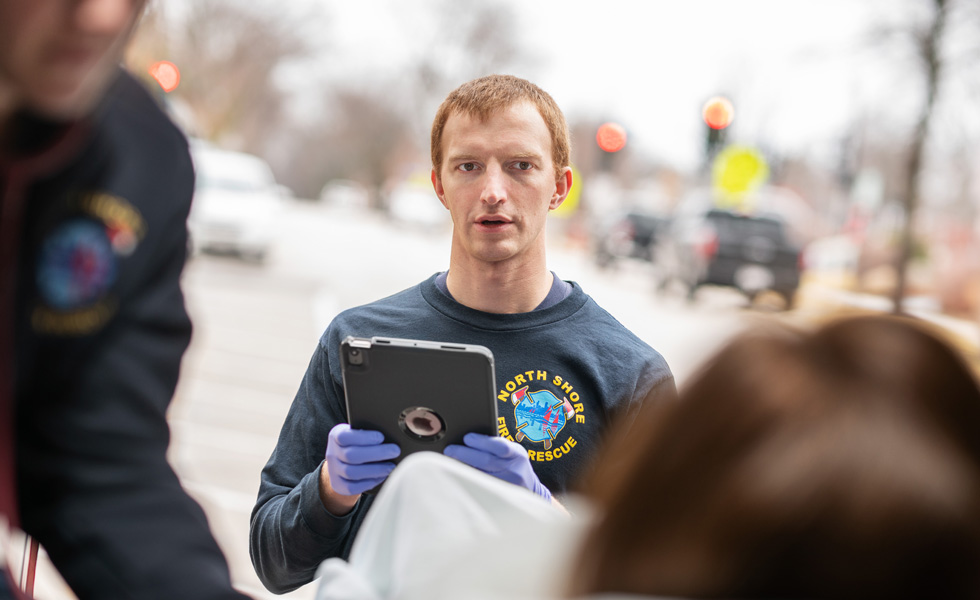 A crew member holding an iPad speaks to a patient inside a medical transport vehicle