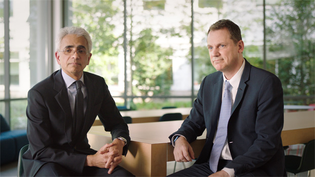 Hai người mặc vest ngồi cùng một bàn.