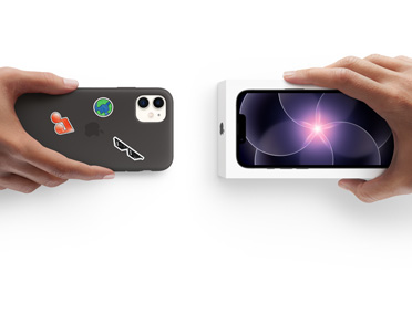 Side-by-side, hand holding iPhone 11 in silicon case with stickers on back exterior, trade-in with hand holding new iPhone box for iPhone 17e