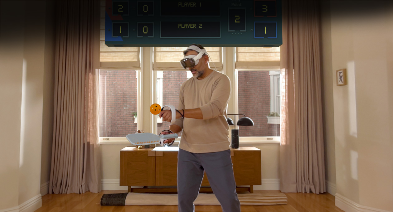 صورة لرجل يرتدي جهاز Apple&nbsp;Vision&nbsp;Pro ومعه وحدة تحكم Sony&nbsp;PlayStation&nbsp;VR2&nbsp;Sense٫، وهو يلعب لعبة Pickle&nbsp;Pro، وتظهر لوحة النتائج المكانية فوق رأسه