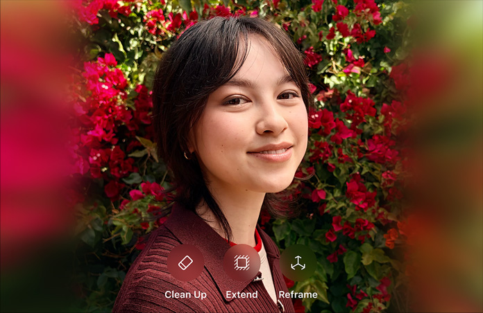 Foto de una persona sonriente de cabello marrón, vistiendo un suéter marrón, rodeada de flores rojas, demostración de edición de fotos con IA con las opciones Borrador, Ampliar y Reencuadrar en la foto