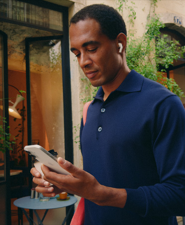 Una persona en la calle de una ciudad mira su iPhone, con una conexión Wi-Fi que se mantiene estable mientras alterna entre diferentes redes