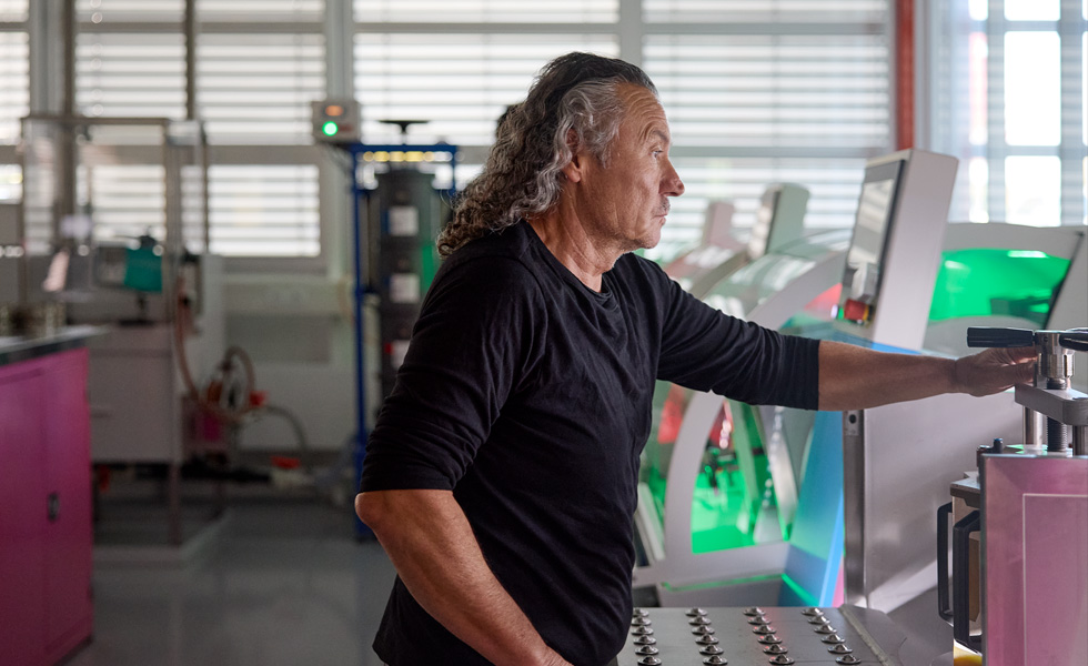 Una persona che lavora davanti a macchinari per la produzione di componenti